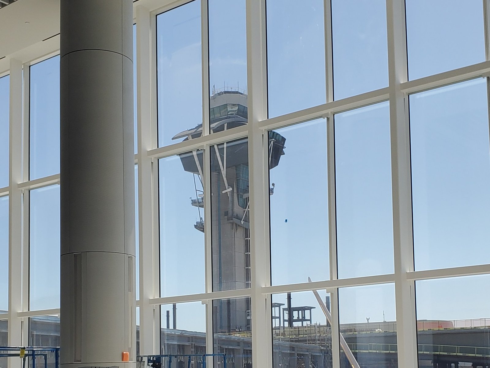 LAX terminal interior under construction, air traffic control tower visible through the windows